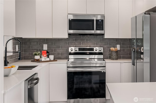 kitchen featuring stainless steel appliances, a sink, light countertops, and white cabinets