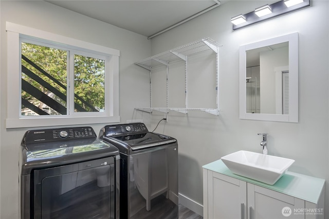 washroom featuring a sink, washer and clothes dryer, wood finished floors, and baseboards