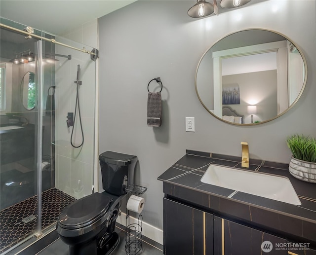 bathroom with toilet, vanity, a shower stall, and baseboards