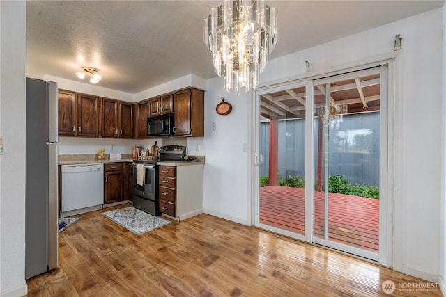 727 Salzburg Ln SE, Olympia, WA 98513 - kitchen with appliances with stainless steel finishes, light wood-style flooring, light countertops, dark brown cabinets, and a chandelier