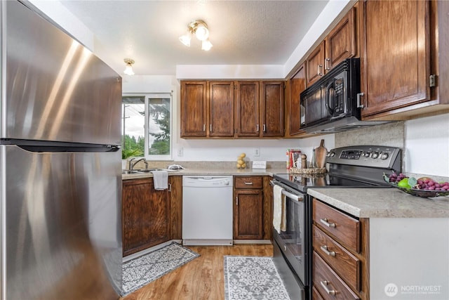 727 Salzburg Ln SE, Olympia, WA 98513 - kitchen featuring appliances with stainless steel finishes, light wood-style flooring, light countertops, a sink, and brown cabinetry