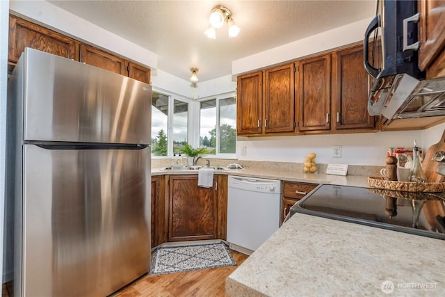 727 Salzburg Ln SE, Olympia, WA 98513 - kitchen with freestanding refrigerator, white dishwasher, a sink, light wood finished floors, and light countertops
