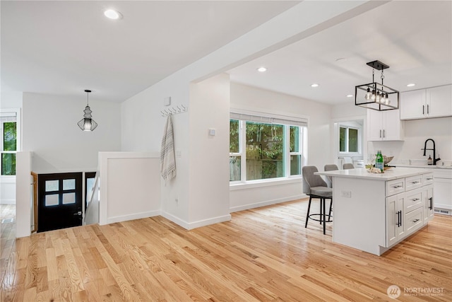 2333 NE 94th St, Seattle, WA 98115 - kitchen featuring a sink, light countertops, a breakfast bar area, white cabinets, and recessed lighting