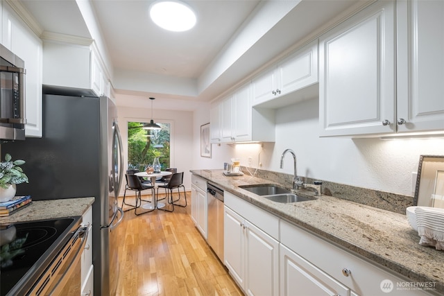 kitchen with stainless steel appliances, a sink, light wood-style flooring, and white cabinets