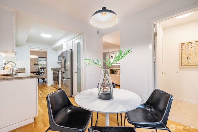 dining area featuring light wood-style flooring and a raised ceiling