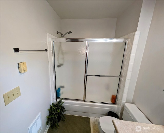full bath featuring toilet and bath / shower combo with glass door