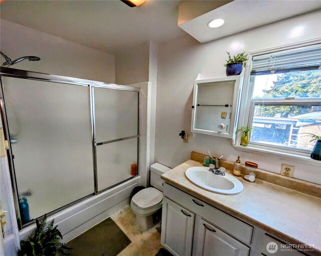 bathroom featuring vanity, toilet, and shower / bath combination with glass door