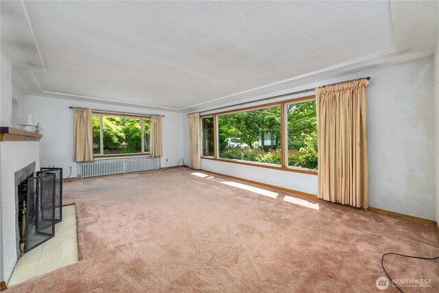 7209 104th St E, Puyallup, WA 98373 - unfurnished living room featuring radiator, carpet, a fireplace with flush hearth, and baseboards