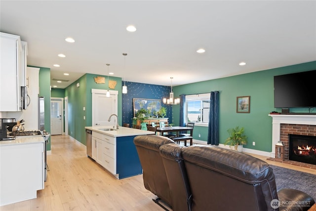 210 E Cedarland Ln, Allyn, WA 98524 - living room featuring light wood-style floors, recessed lighting, a chandelier, baseboards, and a brick fireplace