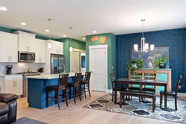 210 E Cedarland Ln, Allyn, WA 98524 - kitchen with appliances with stainless steel finishes, a chandelier, light wood finished floors, a breakfast bar, and recessed lighting