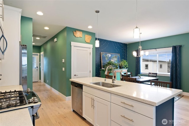 210 E Cedarland Ln, Allyn, WA 98524 - kitchen featuring a sink, stainless steel dishwasher, white cabinets, light wood-style floors, and decorative light fixtures