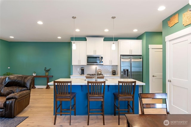 210 E Cedarland Ln, Allyn, WA 98524 - kitchen featuring stainless steel appliances, open floor plan, light countertops, light wood-type flooring, and backsplash