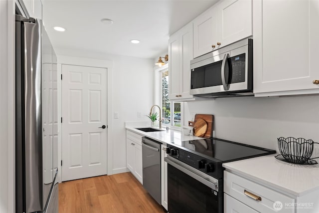 3009 Heath Ct, Steilacoom, WA 98388 - kitchen with appliances with stainless steel finishes, a sink, light wood-style floors, white cabinetry, and recessed lighting