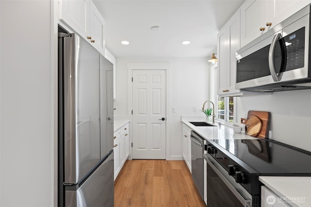 3009 Heath Ct, Steilacoom, WA 98388 - kitchen featuring stainless steel appliances, a sink, light wood-type flooring, light countertops, and white cabinetry