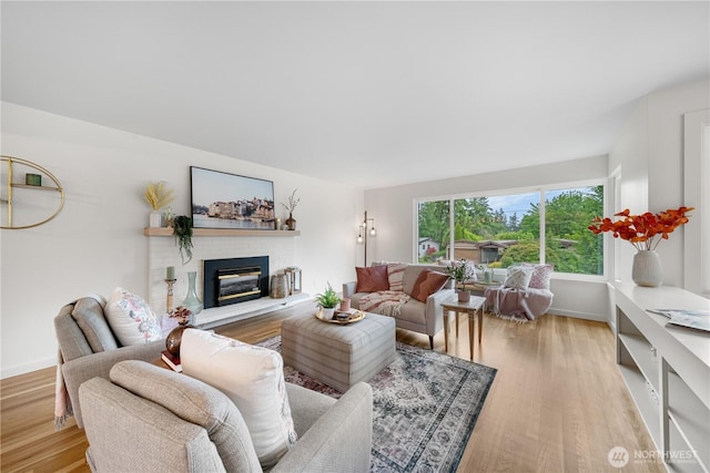living room featuring a brick fireplace, wood finished floors, and baseboards