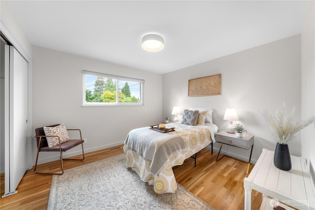 bedroom with light wood-style floors, baseboards, and a closet