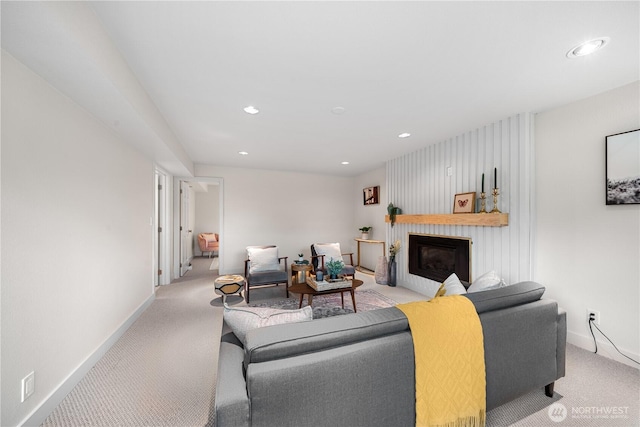 living area featuring baseboards, light carpet, recessed lighting, and a glass covered fireplace