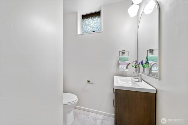 half bath with tile patterned floors, vanity, toilet, and baseboards