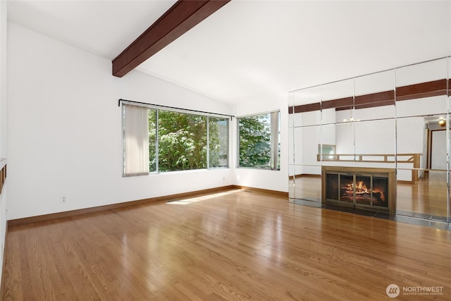 1006 N 36th St, Renton, WA 98056 - unfurnished living room with wood finished floors, beam ceiling, baseboards, a glass covered fireplace, and high vaulted ceiling