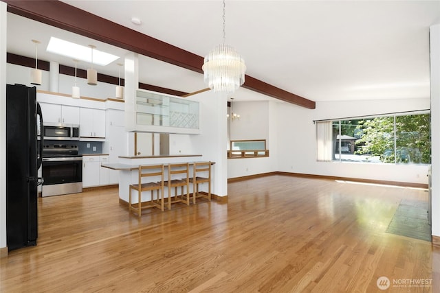 1006 N 36th St, Renton, WA 98056 - kitchen with appliances with stainless steel finishes, beam ceiling, a chandelier, white cabinetry, and light wood finished floors