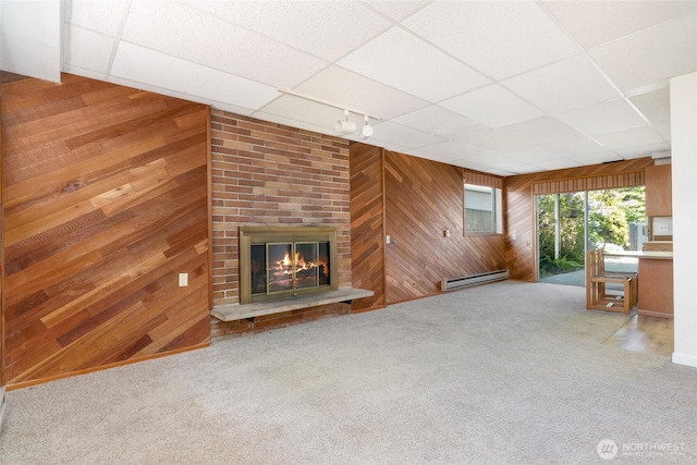 1006 N 36th St, Renton, WA 98056 - unfurnished living room featuring wood walls, a drop ceiling, baseboard heating, carpet, and a brick fireplace