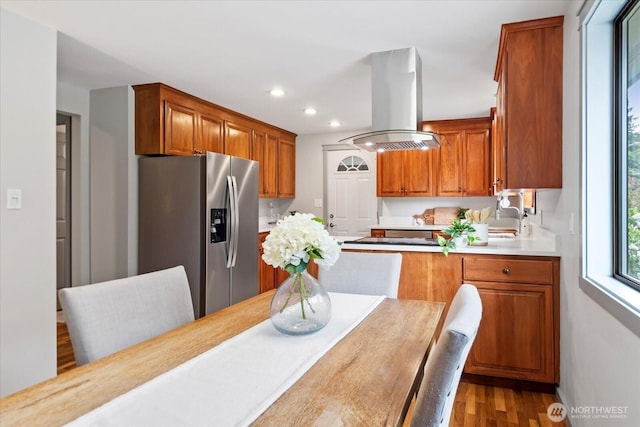 7517 Olympic View Dr, Edmonds, WA 98026 - kitchen with stainless steel fridge with ice dispenser, island range hood, light countertops, brown cabinetry, and recessed lighting