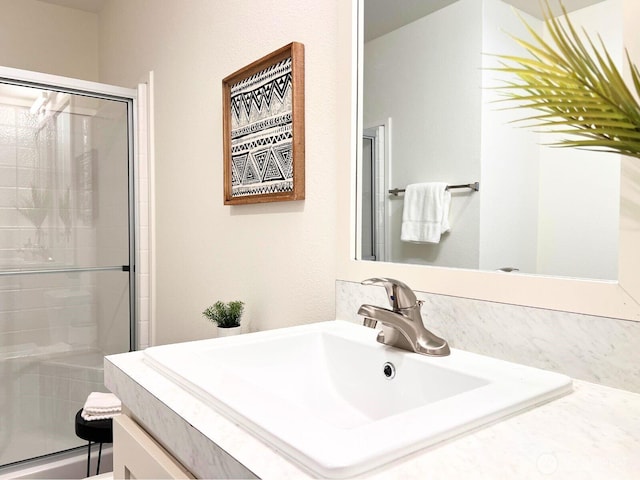 bathroom featuring a shower with shower door and vanity