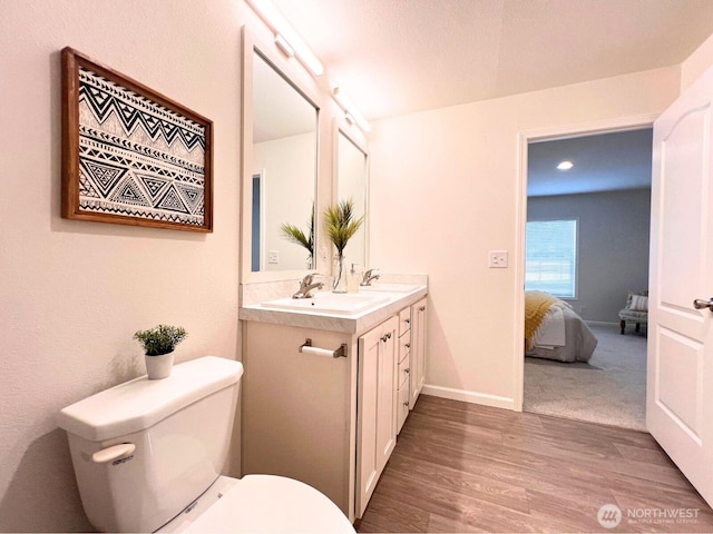 full bath featuring wood finished floors, toilet, double vanity, ensuite bathroom, and recessed lighting