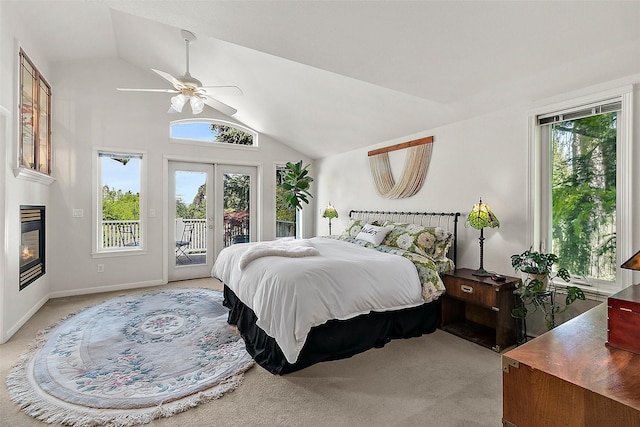 bedroom with vaulted ceiling, multiple windows, light carpet, access to outside, and a glass covered fireplace