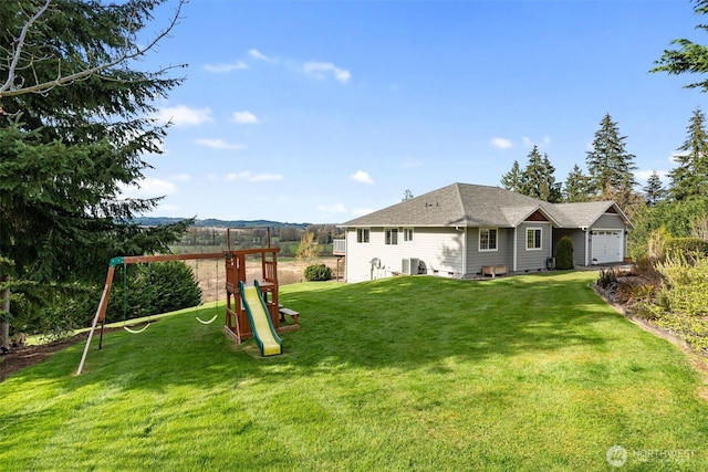 247 Devereese Rd, Chehalis, WA 98532 - rear view of property featuring a playground, a yard, an attached garage, central air condition unit, and roof with shingles