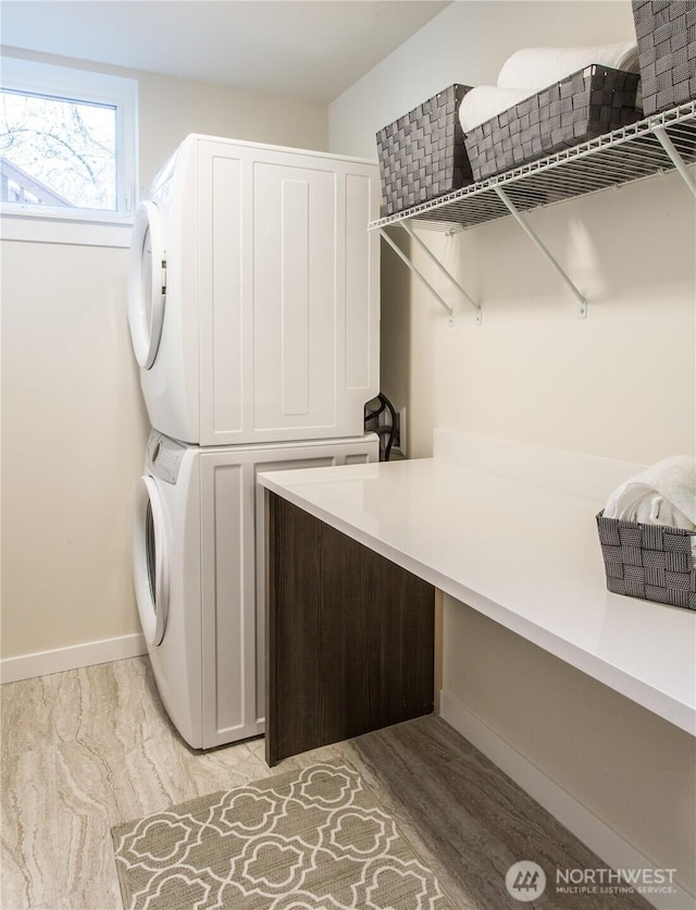 laundry room with stacked washer and clothes dryer and baseboards