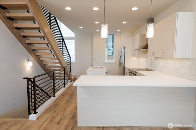 kitchen with a sink, appliances with stainless steel finishes, recessed lighting, light countertops, and light wood-type flooring
