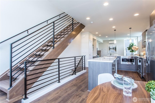 kitchen with stainless steel appliances, dark wood-style flooring, light countertops, a wall mounted air conditioner, and recessed lighting