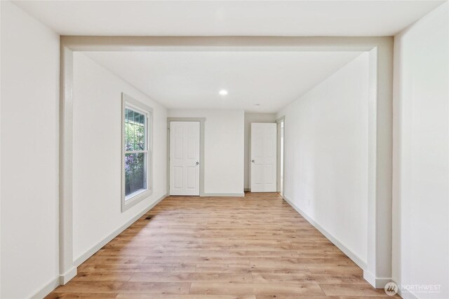 empty room featuring light wood finished floors, recessed lighting, and baseboards