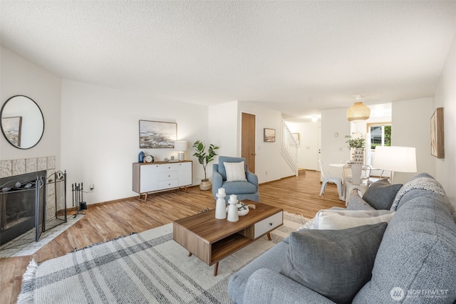 1820 SW 318th Pl Unit 26D, Federal Way, WA 98023 - living room with light wood-type flooring, a fireplace, a textured ceiling, and stairway