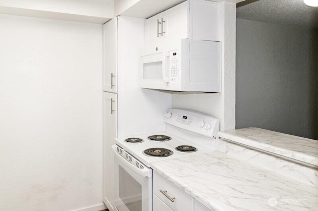 kitchen featuring white appliances, white cabinetry, and light stone countertops