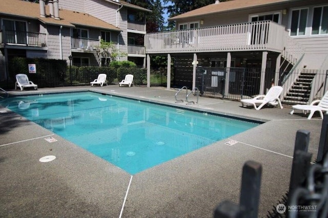 community pool with stairway and a patio