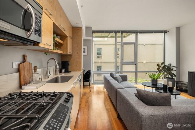 2911 2nd Ave Unit 411, Seattle, WA 98121 - kitchen featuring stainless steel appliances, a sink, light countertops, light wood-style floors, and floor to ceiling windows
