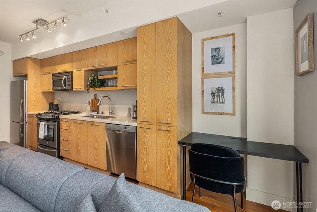 2911 2nd Ave Unit 411, Seattle, WA 98121 - kitchen featuring stainless steel appliances, a sink, an office area, wood finished floors, and light countertops