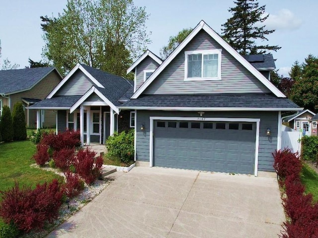 view of front of property with driveway, a garage, and roof mounted solar panels