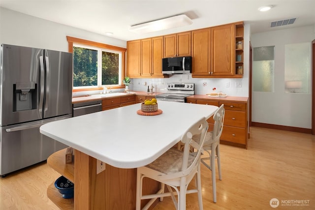 11607 SW Cove Rd, Vashon, WA 98070 - kitchen featuring stainless steel appliances, open shelves, a sink, and light wood-type flooring
