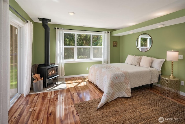11607 SW Cove Rd, Vashon, WA 98070 - bedroom featuring a wood stove, wood finished floors, baseboards, and multiple windows