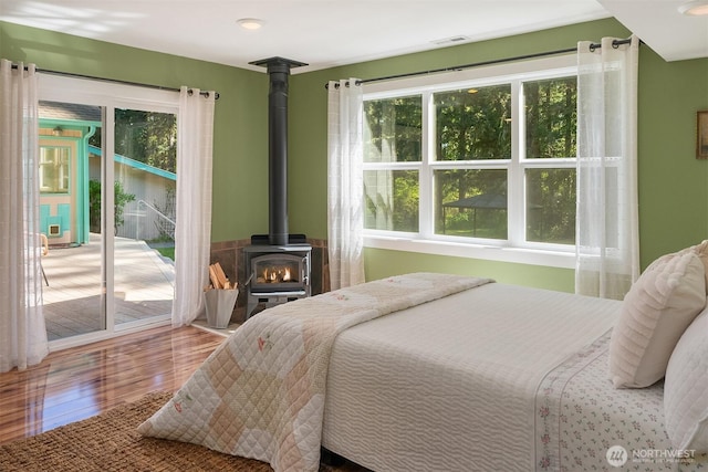 11607 SW Cove Rd, Vashon, WA 98070 - bedroom with access to outside, wood finished floors, and a wood stove