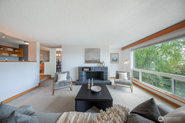 living room featuring a textured ceiling, carpet floors, baseboards, and a fireplace