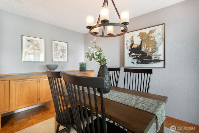 dining room featuring a chandelier, a textured ceiling, and a textured wall