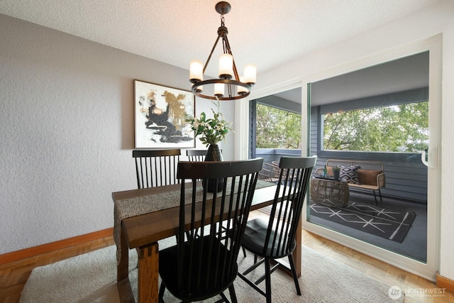 dining room featuring a textured wall, baseboards, a chandelier, parquet floors, and a textured ceiling