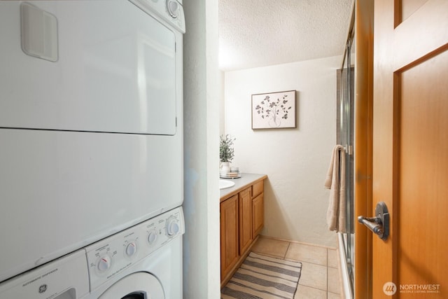 bathroom featuring estacked washer and dryer, a textured ceiling, vanity, and tile patterned flooring