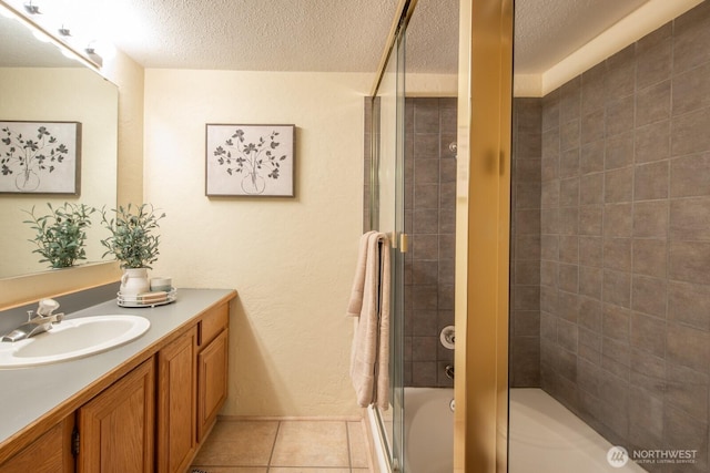 bathroom with a textured ceiling, vanity, tile patterned floors, and tiled shower / bath