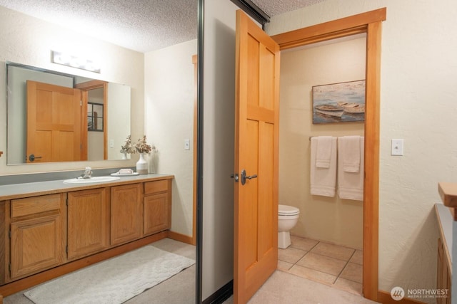 bathroom with a textured ceiling, toilet, and vanity