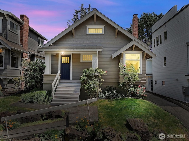 craftsman-style house with a porch, a front yard, and a chimney